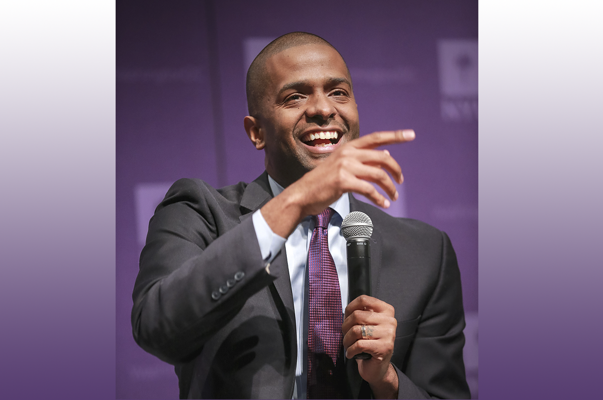 Man in suit holding microphone, smiling and gesturing